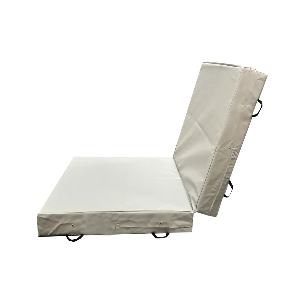 Folding safety mat partially open, two thick foam panels with heavy-duty PVC cover, visible seams and carry handles.