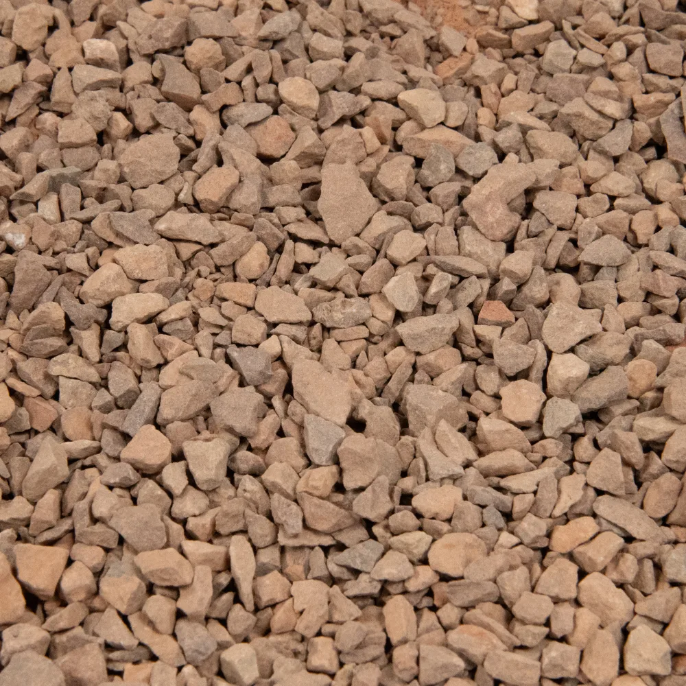 Shot put area red limestone self-binding gravel forming a loose layer of angular red stones.