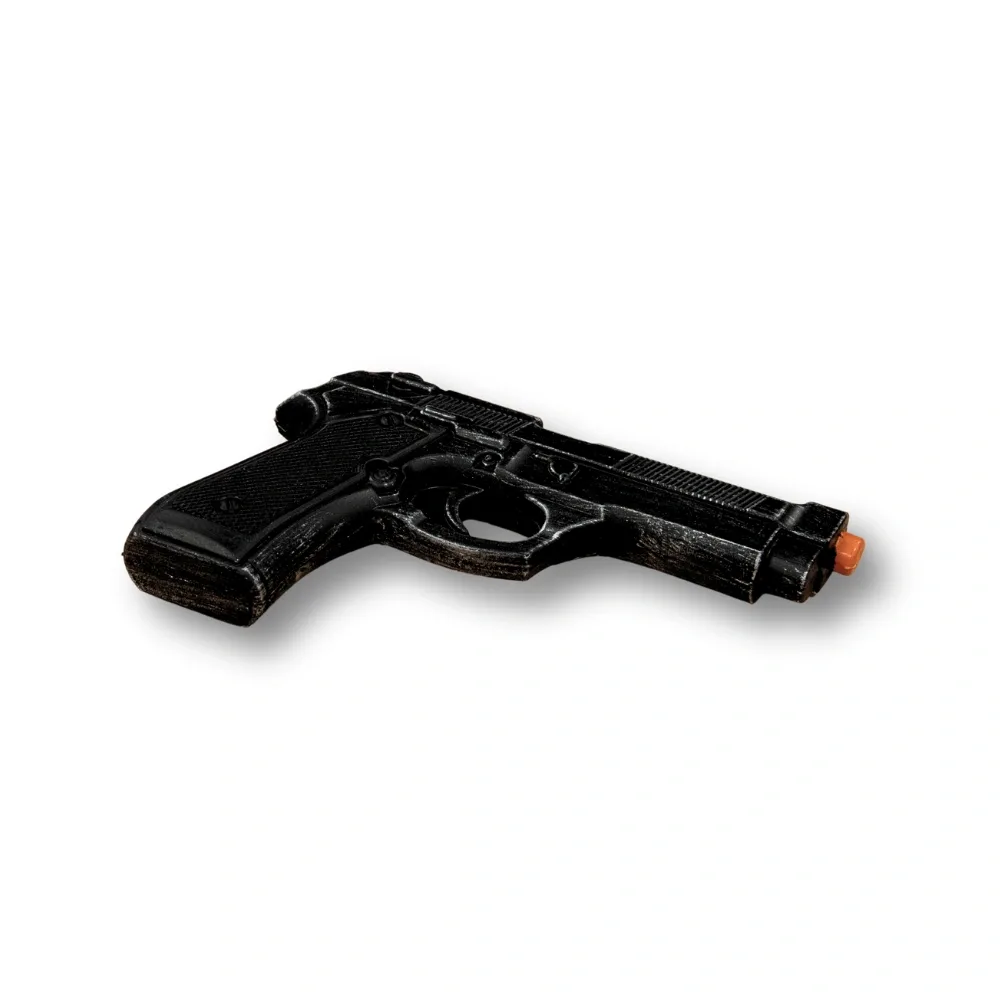 Black realistic gun prop with an orange safety tip resting on a white background.