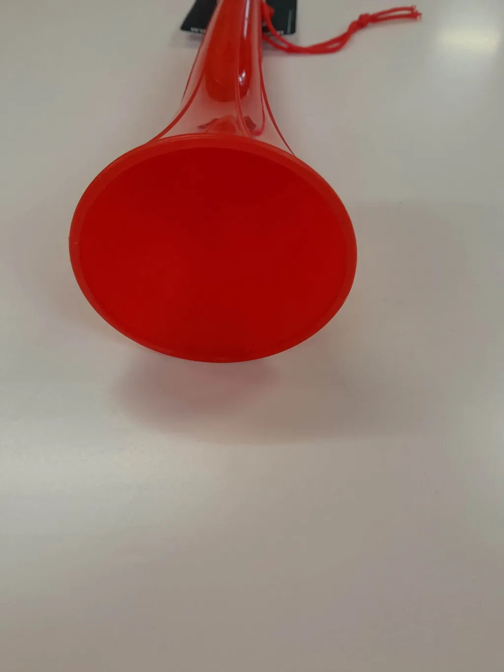 Red plastic warning horn with its flared bell facing forward and a thin handle with an attached cord.