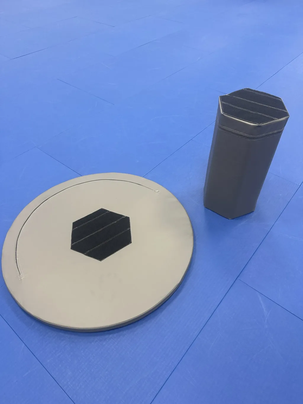 Round foam training table top with hexagonal foam support, both covered in heavy-duty PVC, on a training mat.