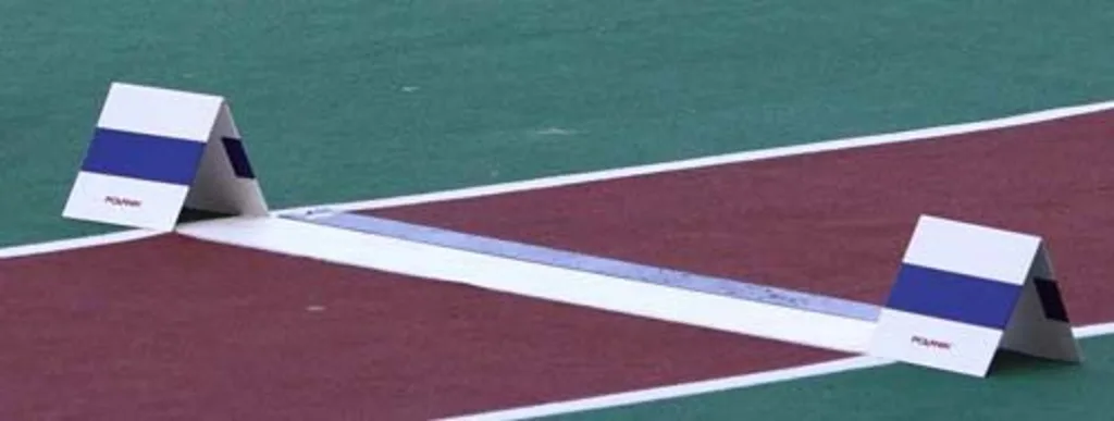 Two aluminium takeoff markers with blue bands flanking a white takeoff board on a red track.