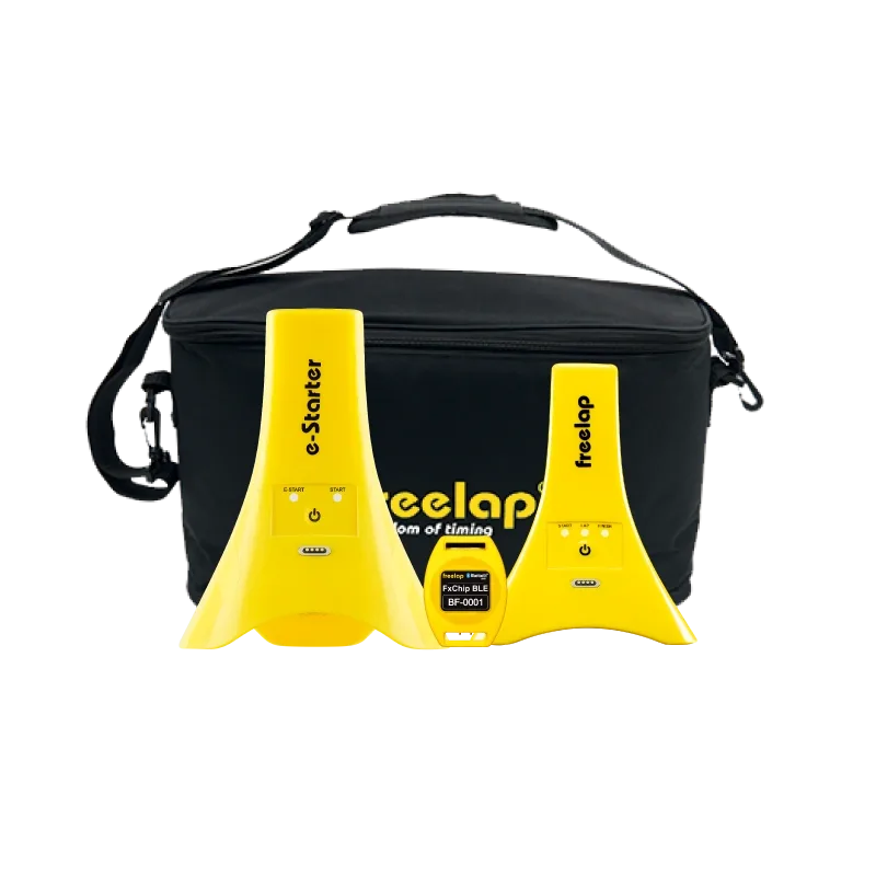 Yellow e-Starter and timing units with a small FxChip BLE labeled 'FxChip BLE BF-0001' placed in front of a black satchel bag reading 'freelap'.