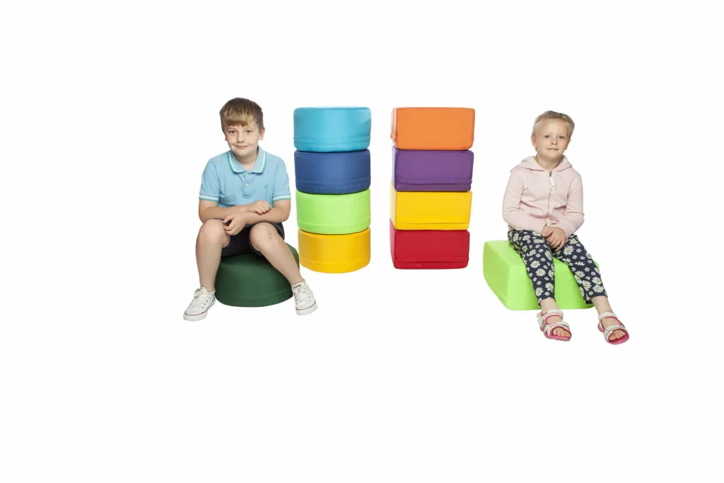 Two children sit on round foam seating pods beside a stacked set of five indoor/outdoor polyester pods.