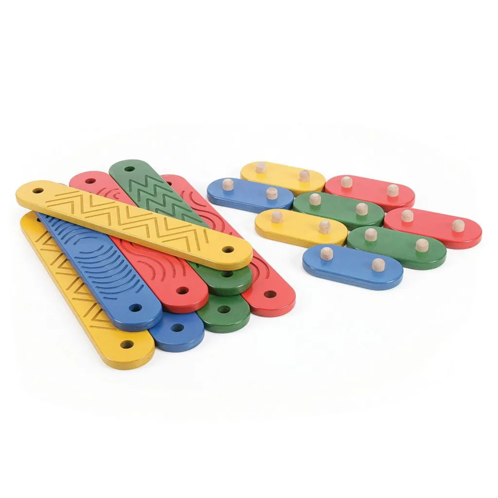 Colorful wooden balance boards in red, blue, green and yellow with engraved zigzag and arc patterns, shown with matching oval connector pieces topped by wooden pegs on white.