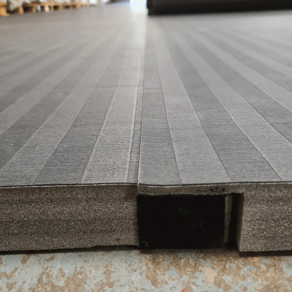 Roll-out PVC hybrid mat with tatami-embossed surface and a visible hook-and-loop connector recessed in the high-density cross-link foam edge.
