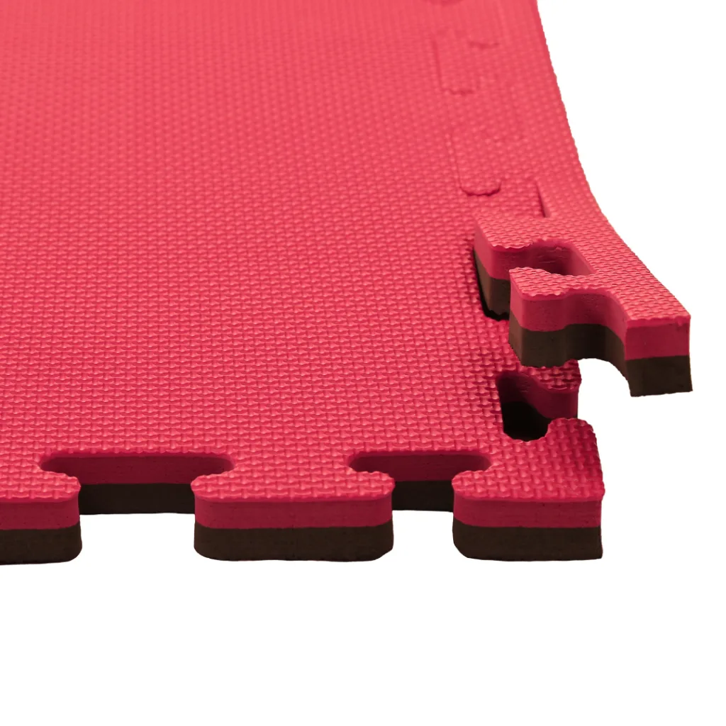 Red and black EVA foam jigsaw mat corner with textured red surface and interlocking puzzle edges showing the black core.
