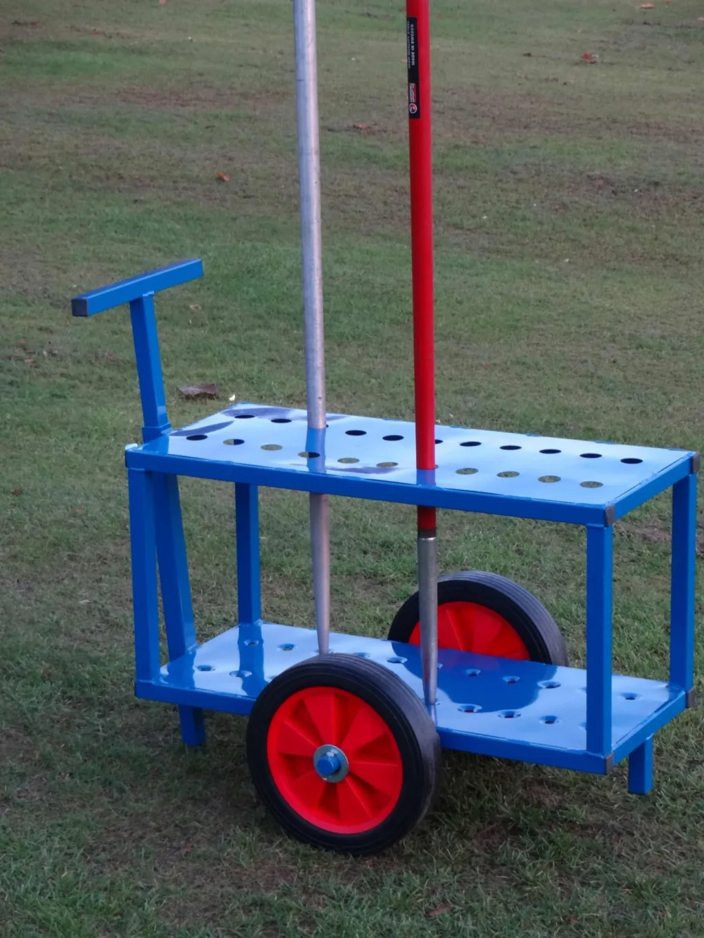 Blue powder-coated steel javelin trolley with two vertical javelins, red wheel hubs and large hard rubber wheels on grass.