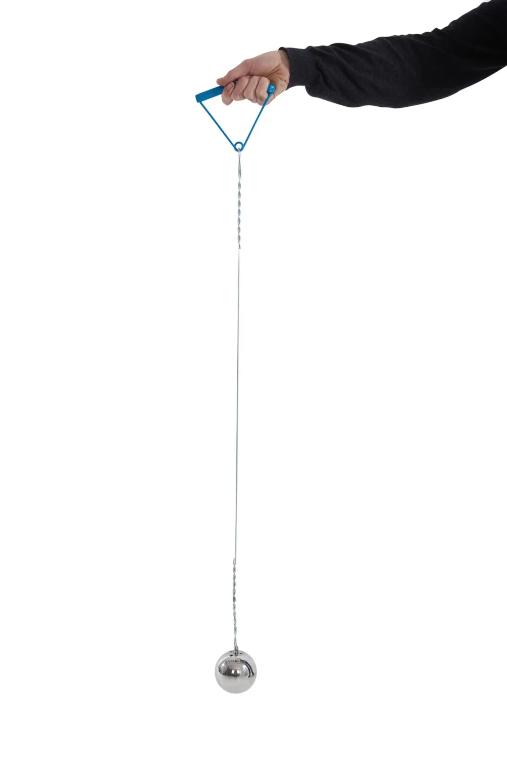 Hand in a dark sleeve holding a blue triangular handle connected to a long stainless steel wire with a shiny stainless steel hammer ball.