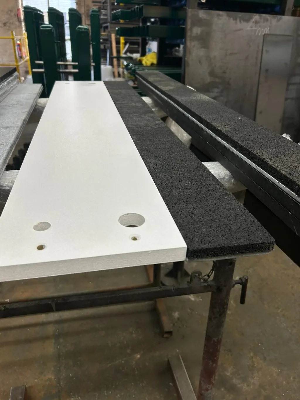 Cantabrian take-off board with pre-drilled wooden top and rubber edging set on galvanised steel supports in a workshop.