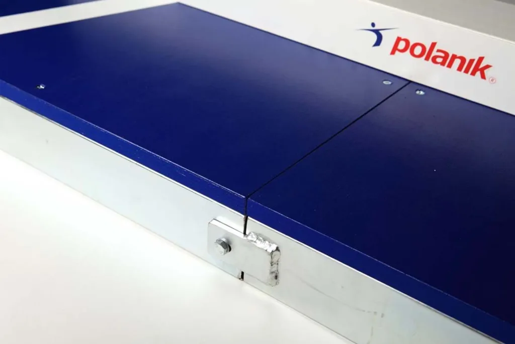Blue plywood throwing circle quadrant with galvanized steel rim, visible seam and bolt hinge, and a white competition toe board at the top edge.