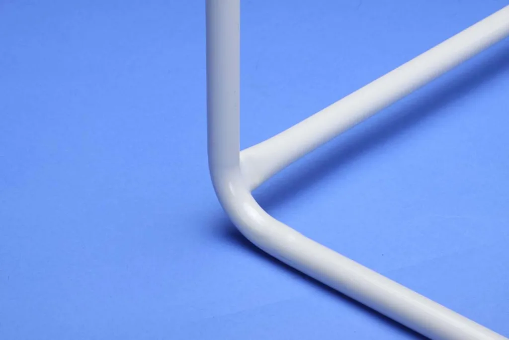 White powder-painted steel tube bent at a 90-degree angle forming the base of a one-piece training hurdle on a blue background.