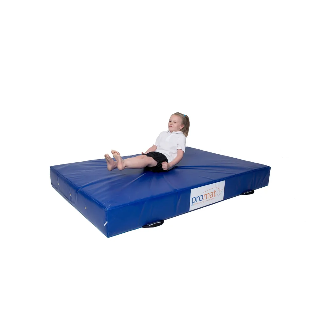 Child sitting on a blue crash mat with PU foam core, zipped nylon-reinforced PVC cover and handles.