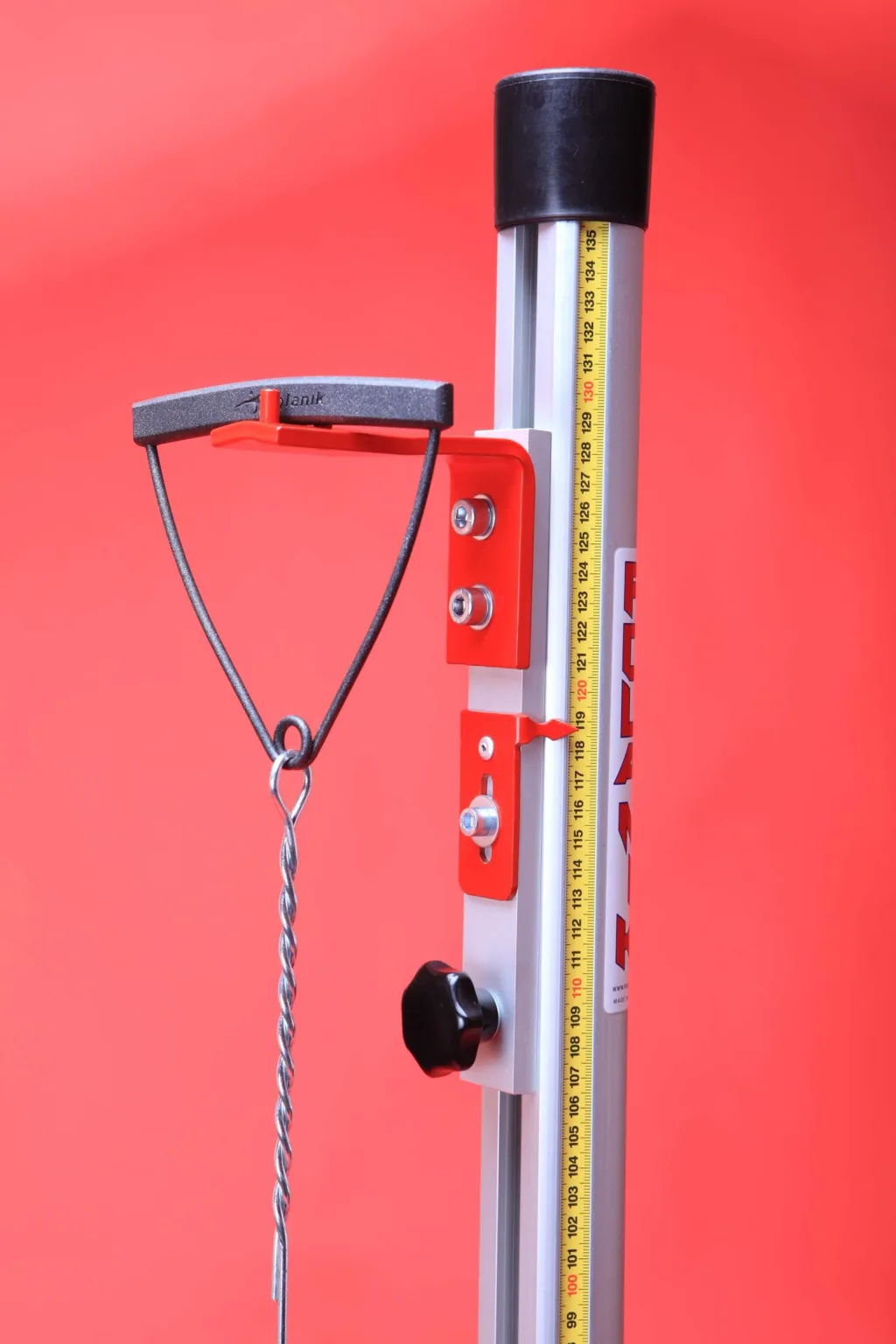 Vertical aluminium and steel hammer measuring device with yellow measuring tape, red adjustment brackets, black top cap, and twisted metal hanger.