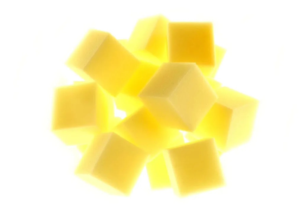 Gym pit foam cubes piled loosely, showing soft square faces of pale coloured foam.