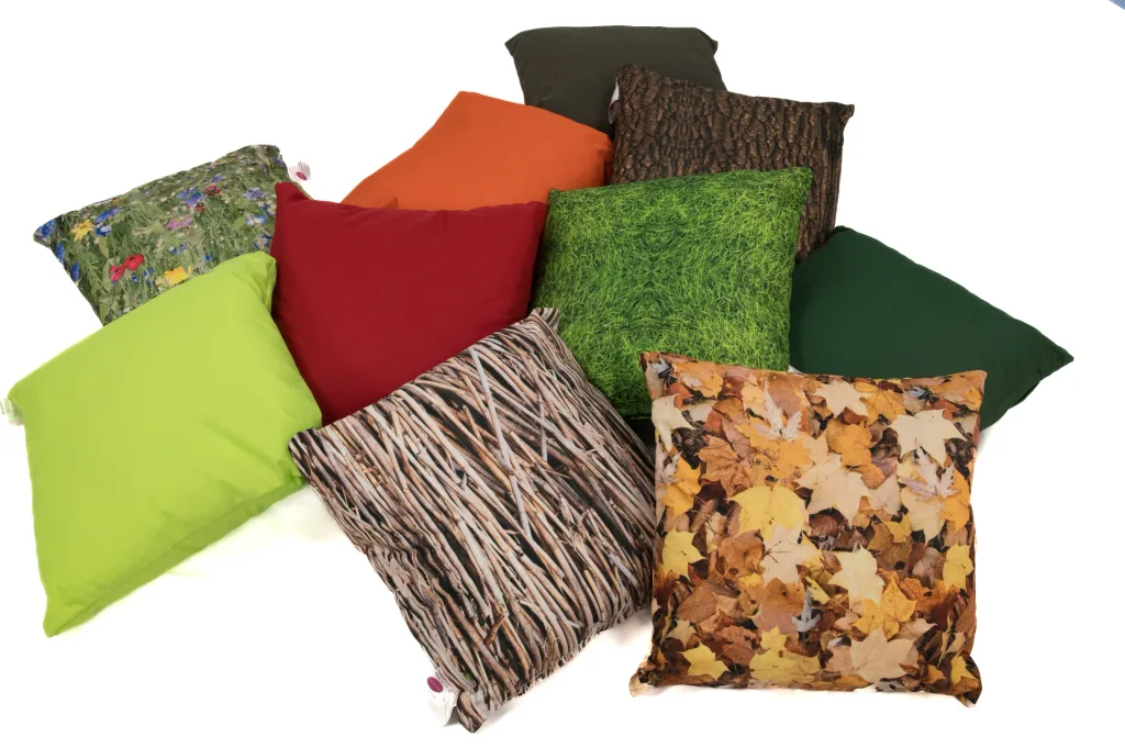 Set of 10 square scatter cushions piled together with nature-themed prints (grass, autumn leaves, bark, twigs, wildflowers) and solid green, red, orange and lime covers.