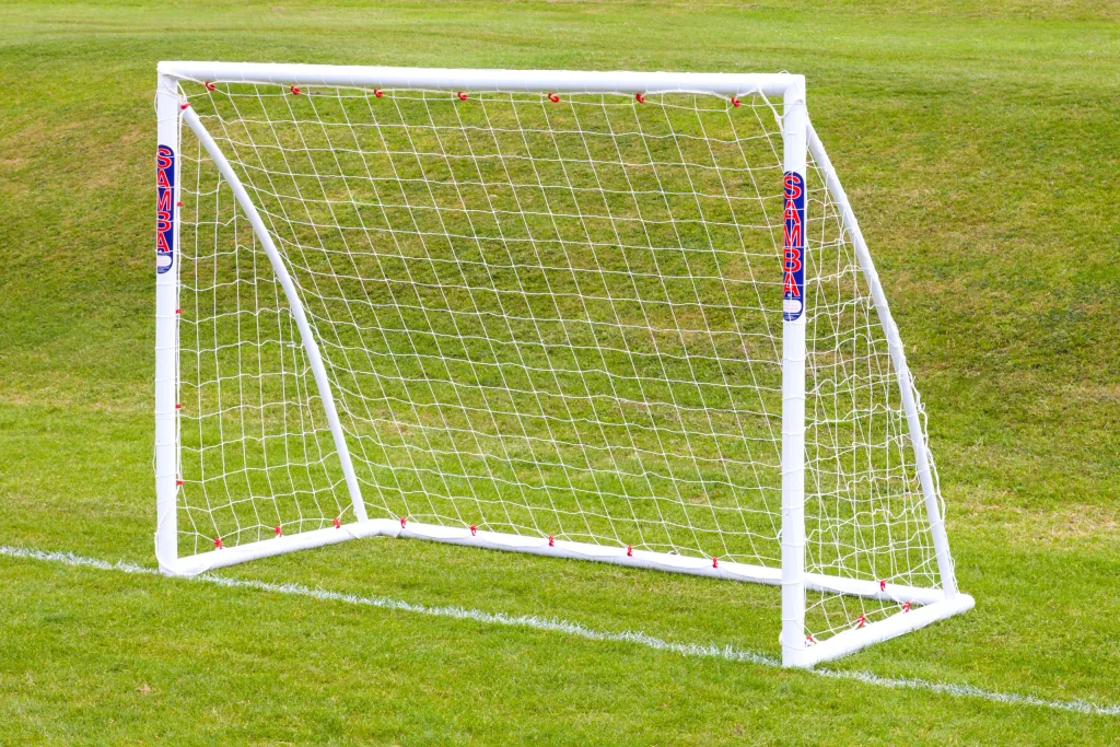 White uPVC freestanding soccer goal with net and vertical SAMBA labels on the posts, set on green grass.