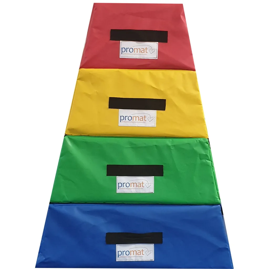 Four stacked PU foam vaulting sections with PVC covers in red, yellow, green and blue, each with black handles and promat labels.