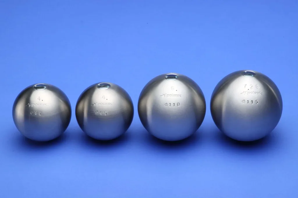 Four stainless steel shot puts of increasing size lined up on a blue background, engraved with "4. Ø95", "4. Ø95", "6. Ø110", and "7.26 Ø115".