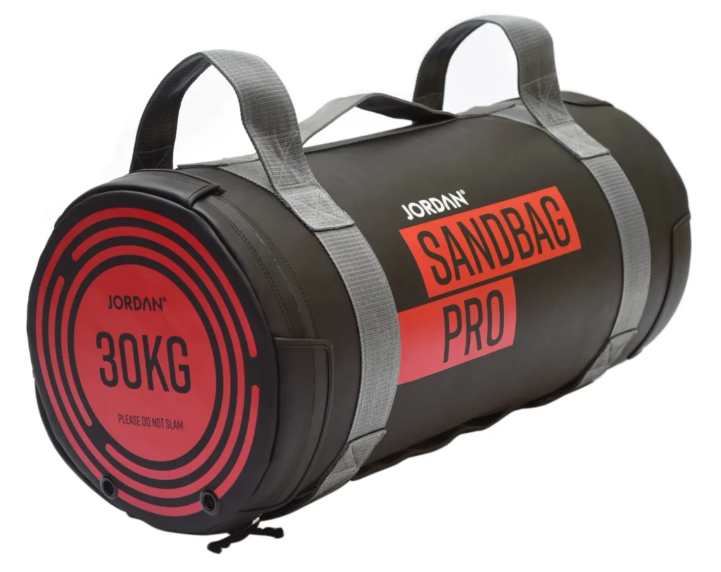 Black cylindrical sandbag with grey webbed handles, red circular end and red side label 'SANDBAG PRO'.