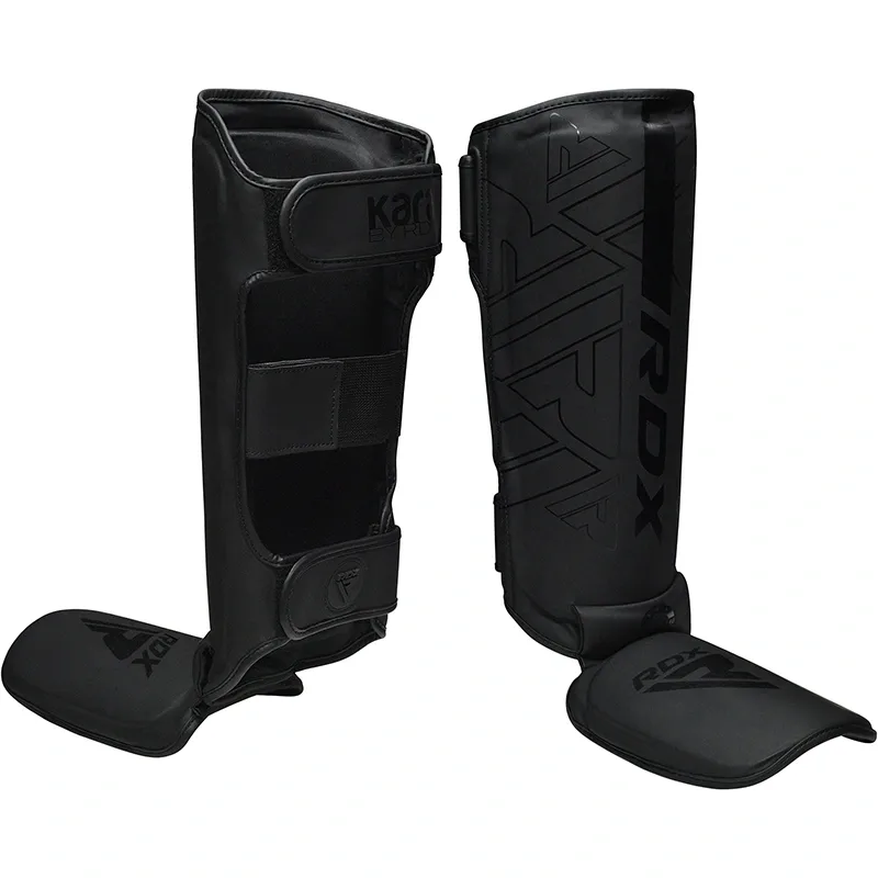 Pair of black MMA shin and instep guards with padded insteps, curved shin panels, and Velcro fastening straps.