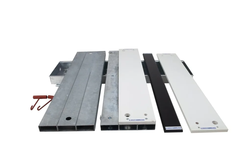 Galvanised steel foundation troughs and blanking boards beside white wood-topped take-off boards, a black no-jump indicator strip, and red lifting hooks.