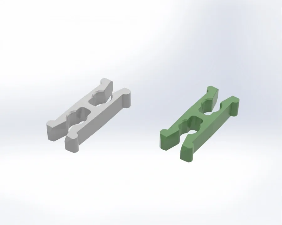 Two elongated interlocking blocks, one gray and one green, with central rounded cutouts and raised ends on a white background.