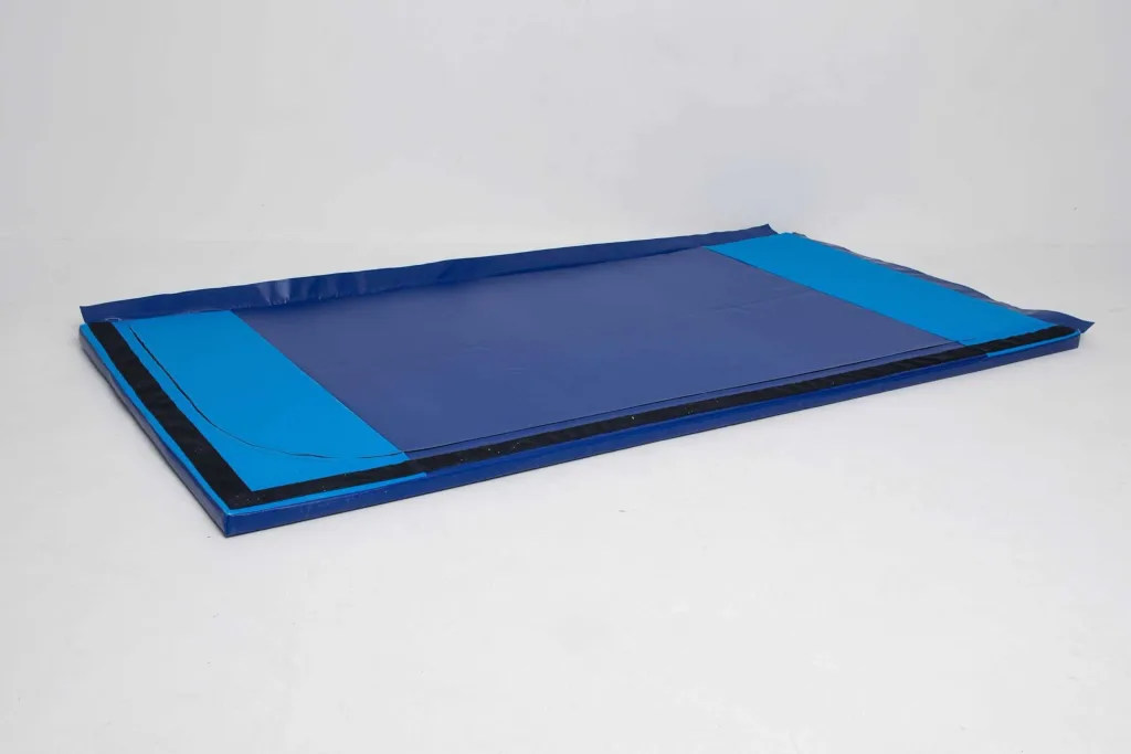 Blue heavy-duty lightweight gym mat with sewn tear-resistant PVC cover and lighter blue end panels, black anti-slip strips on the base.