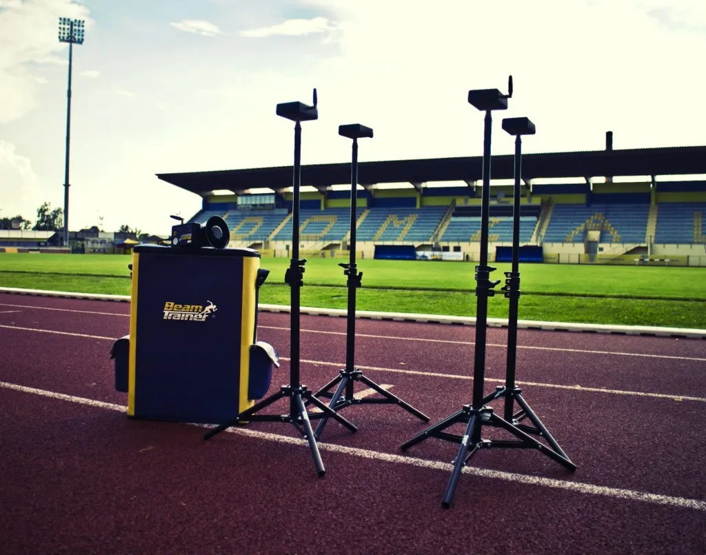 Running timing gates with four IR sensors on tripods beside a blue and yellow bag labeled Beam Trainer on a track.