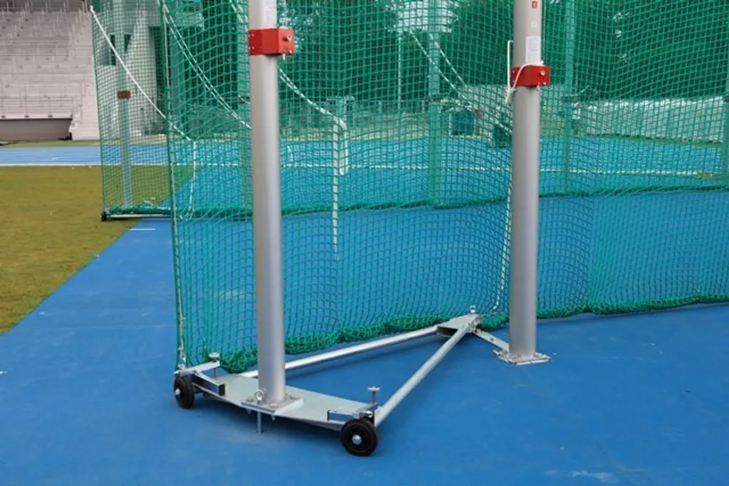 Aluminium vertical posts with green safety netting and a wheeled triangular base on a blue throwing surface.
