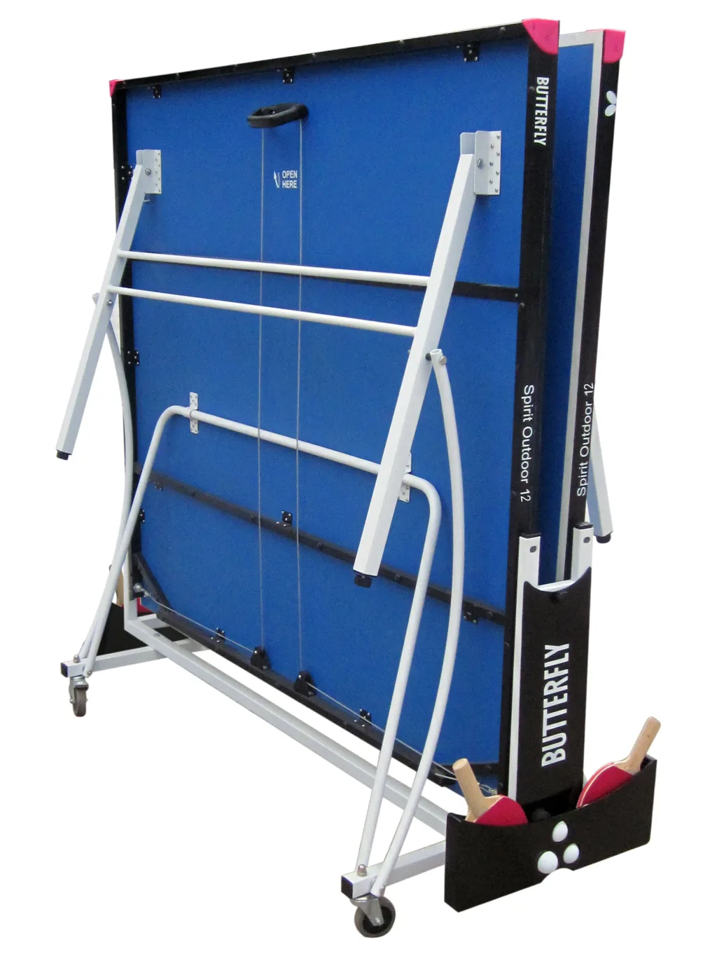 Folded blue outdoor ping-pong table with light silver legs, magenta corner protectors, bat holder with two red bats and three white balls, showing open here text.