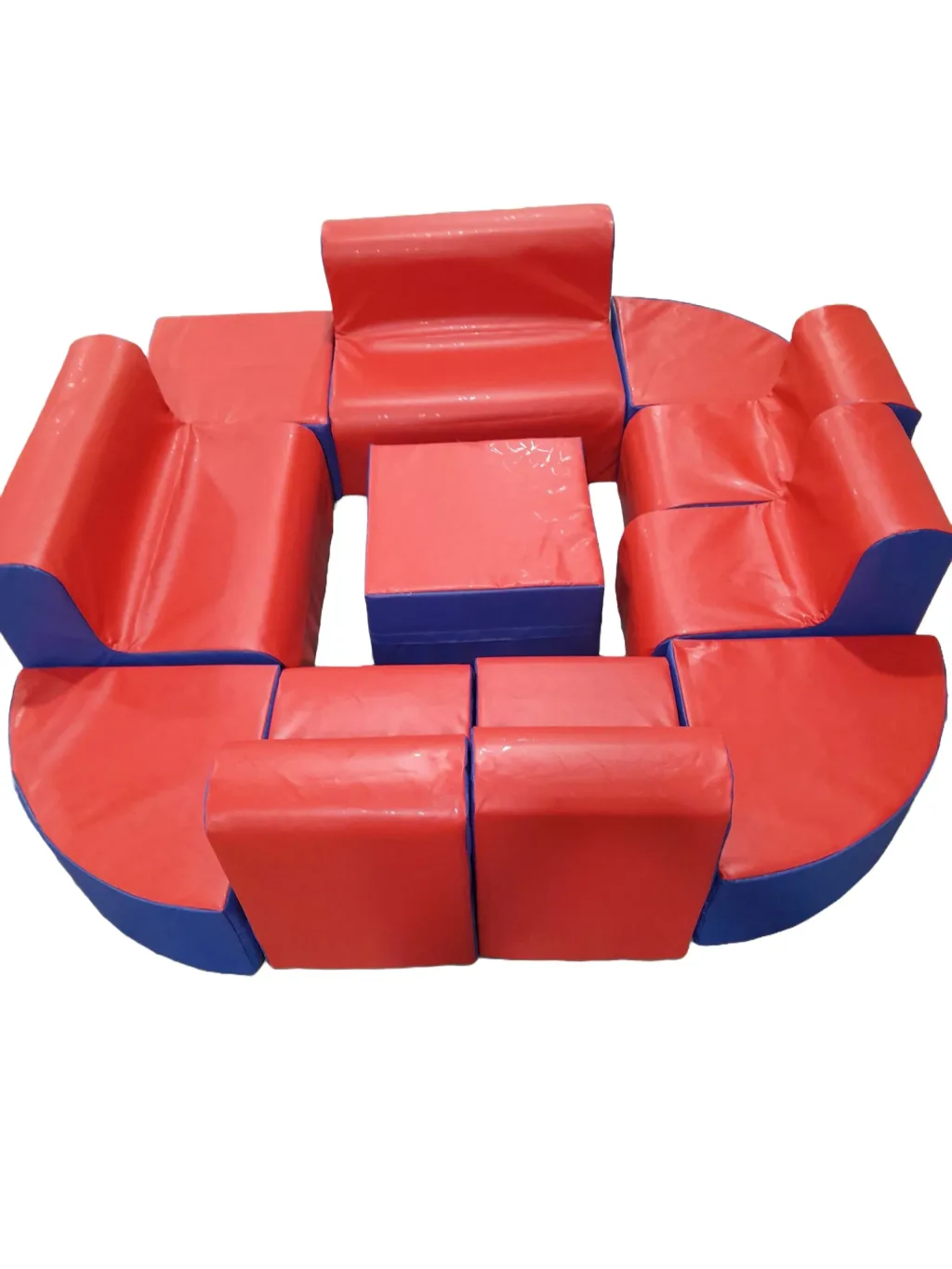 A set of red-topped, blue-sided foam-filled wedge pouffes for children with PVC covers arranged in a circular seating layout.