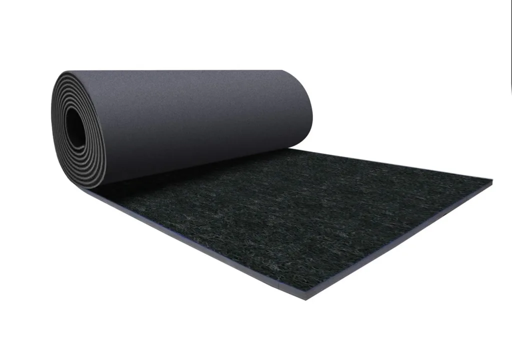 Rolled dark grey gymnastics carpet mat with textured black polypropylene carpet top and layered polyethylene foam backing visible at the edge.