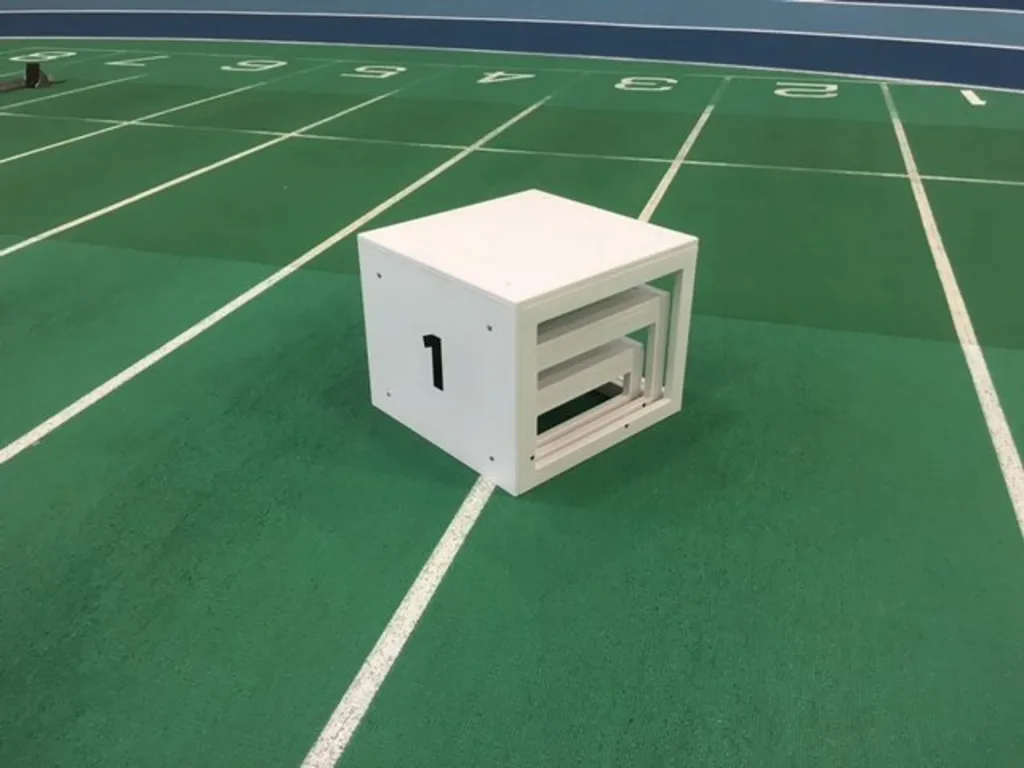 Winners podium composed of three nested white boxes with the number 1 on the side, set on a green indoor running track.