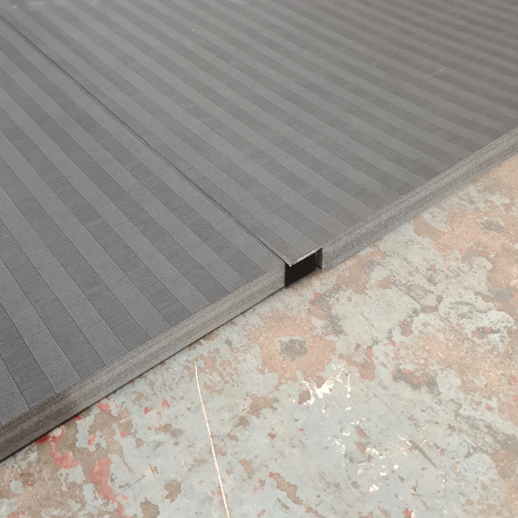 Roll-out PVC mat with low-profile tatami emboss showing a seam and hook-and-loop connector channel on a worn concrete floor.