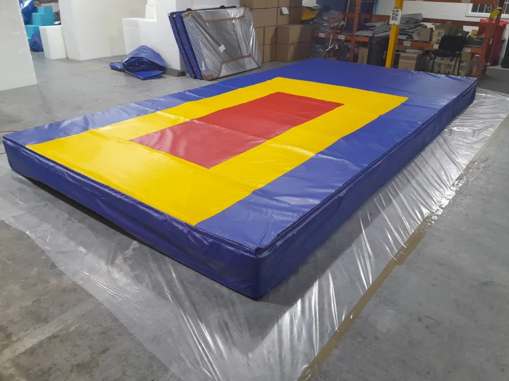 Large rectangular landing mat composed of three modules with a red center and yellow landing area, set on a warehouse floor.