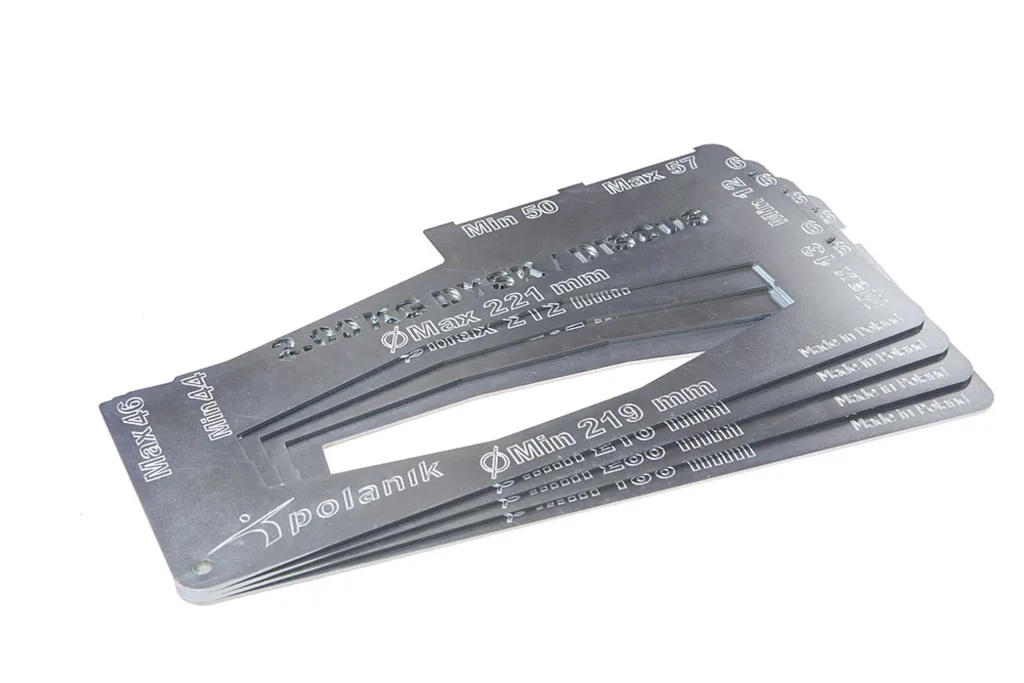 Stacked metal implement certification gauge templates with rectangular cutouts and stenciled markings, including the text Made in Poland.