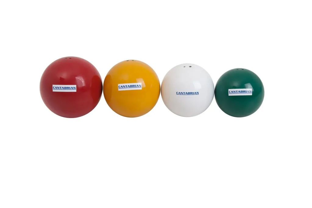 Four painted shot put balls in red, yellow, white, and green lined up on a white background.