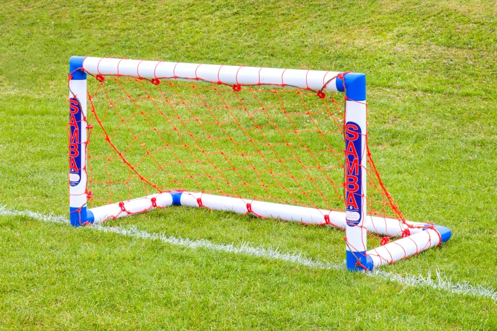 Small freestanding white and blue uPVC soccer goal with red netting and the text SAMBA on the posts.