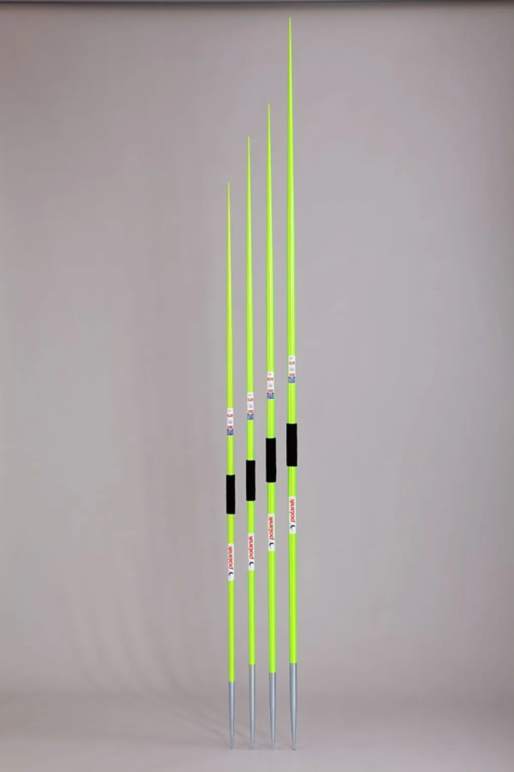 Four fluorescent green javelins with zinc-coated pointed tips and black grip wraps standing upright against a gray background.