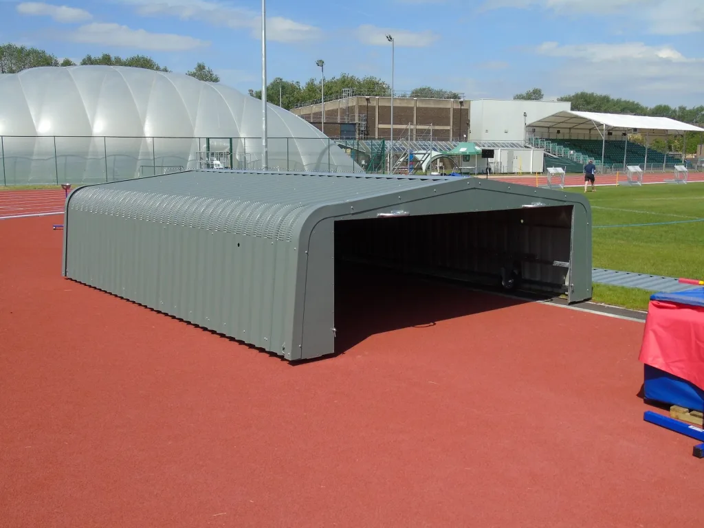 High jump wheel away cover with galvanised welded steel frame and electro galvanised cladding coated in 2 part epoxy paint, open on a red track.