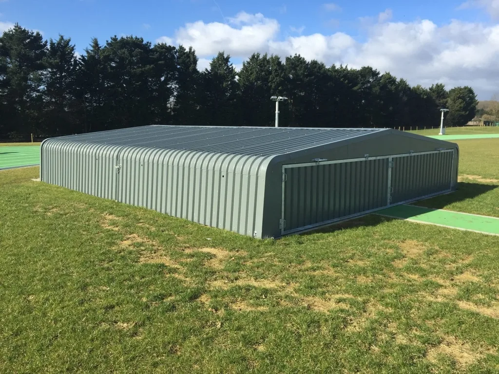High jump wheel-away covers of galvanised welded steel with electro-galvanised cladding and two-part epoxy coating, lowered flush on grass.