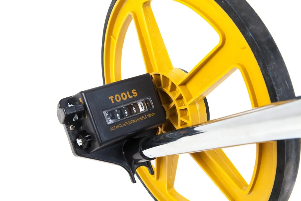 Yellow measuring wheel with black counter labeled TOOLS, small text DISTANCE MEASURING WHEELS 10000M and numeric display 09998.