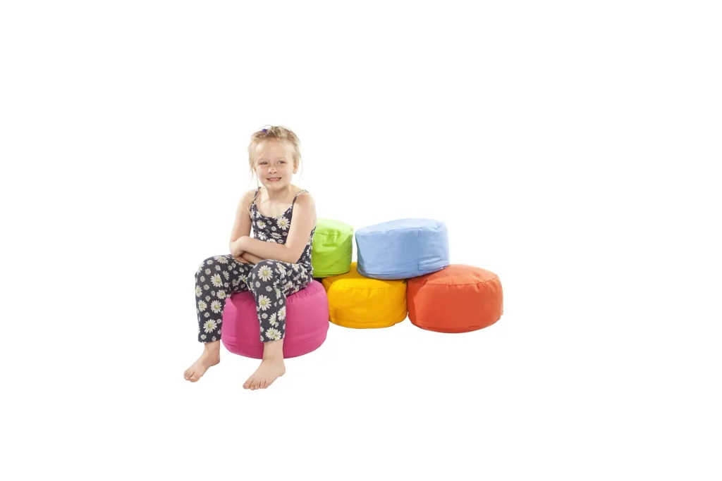 Child sitting on a pink cotton round bean pod with a stack of green, blue, yellow, and orange pods behind her.