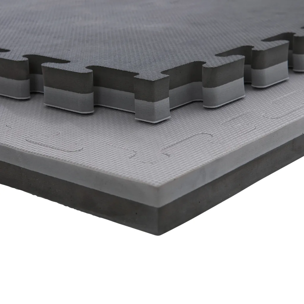 Stacked grey and black EVA foam jigsaw mats showing interlocking tabs, layered profile, and textured surface.