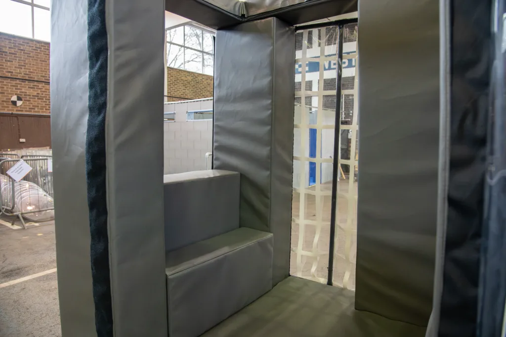 Reinforced foam van cage with heavy-duty PVC cover and an interior two-step padded seat, shown inside an indoor warehouse space.