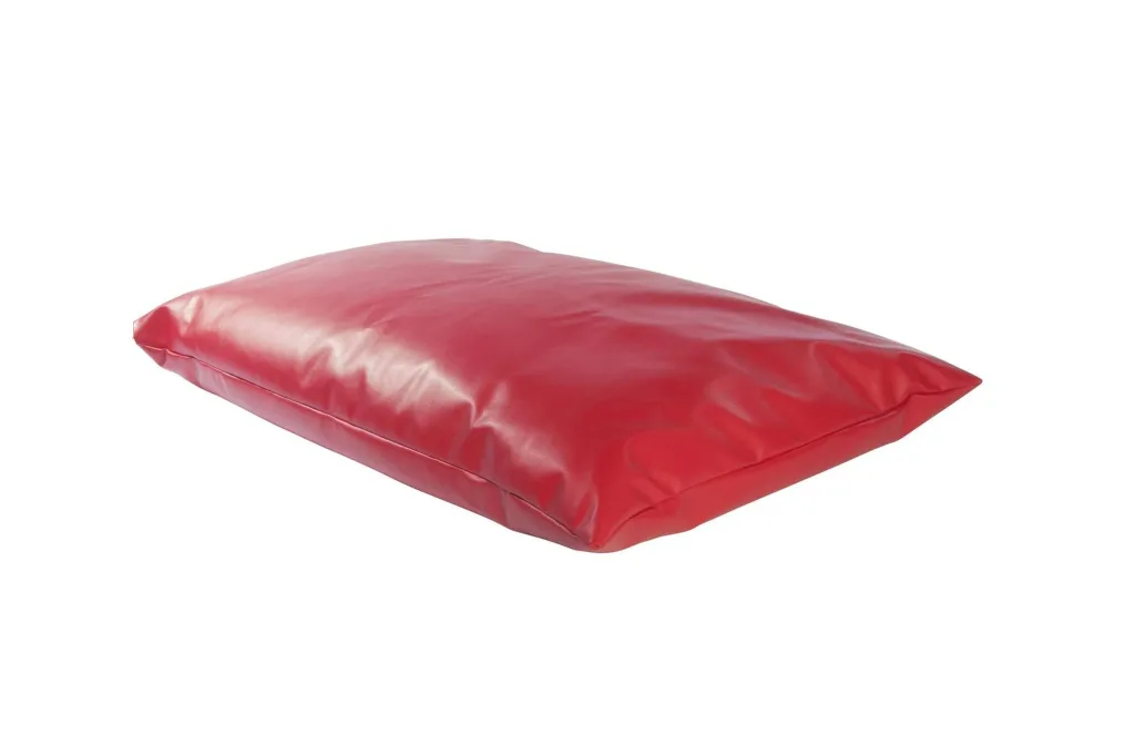 Red faux leather floor cushion, rectangular and low-profile with a visible side seam and slightly wrinkled surface.