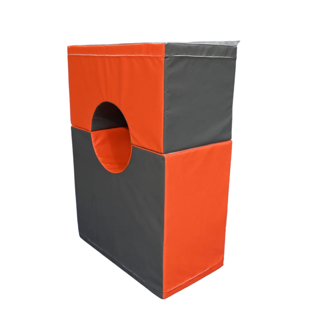 Orange and grey foam gymnastics play set pieces stacked to form a rectangular tunnel with a circular opening.