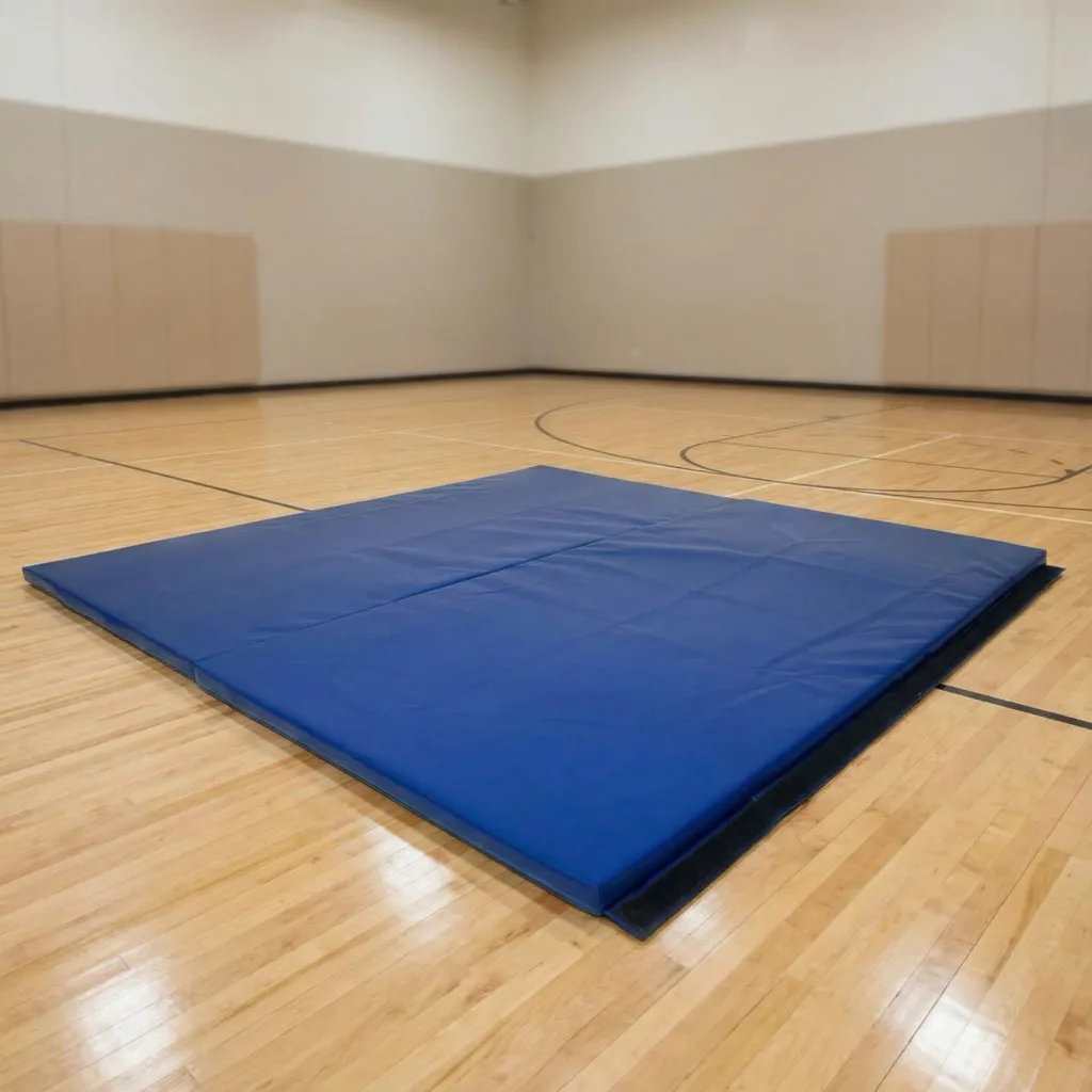 Blue heavy-duty mat with sewn PVC cover and hook and loop edge lying on a wooden gym floor in an empty sports hall.