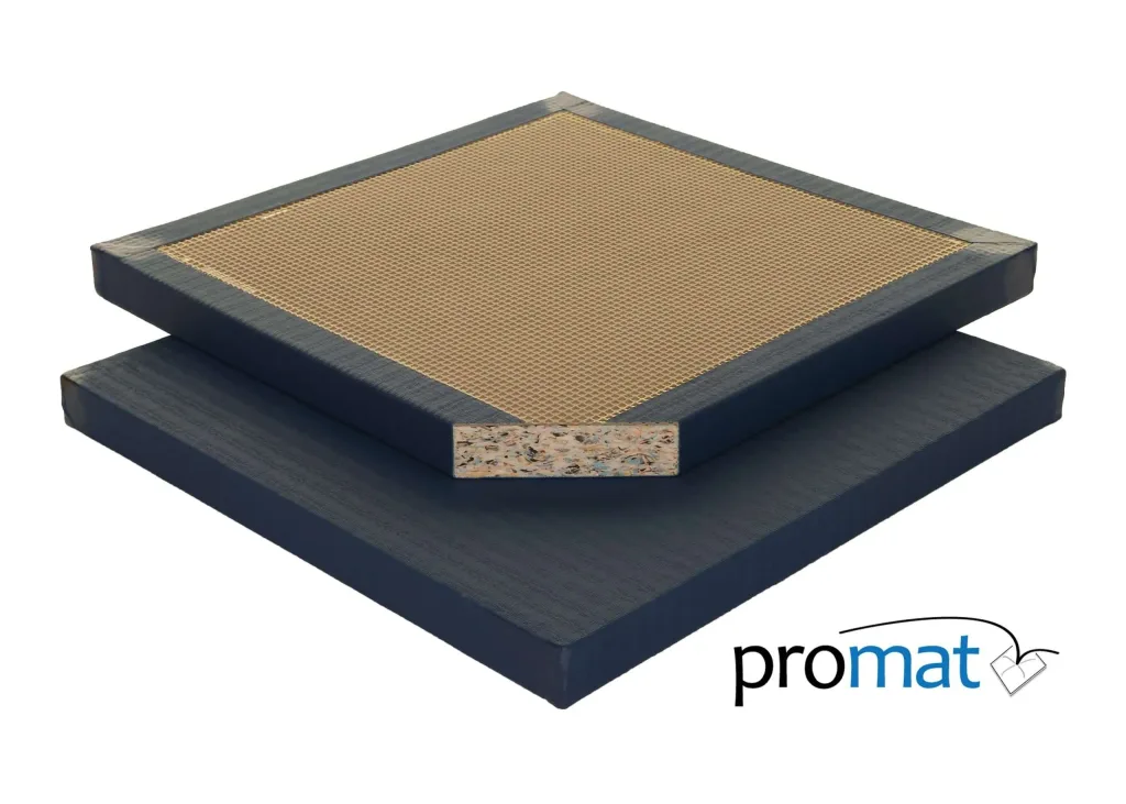 Stacked blue judo mats with tatami-embossed tan top, foam chip core exposed on one edge and promat logo visible.